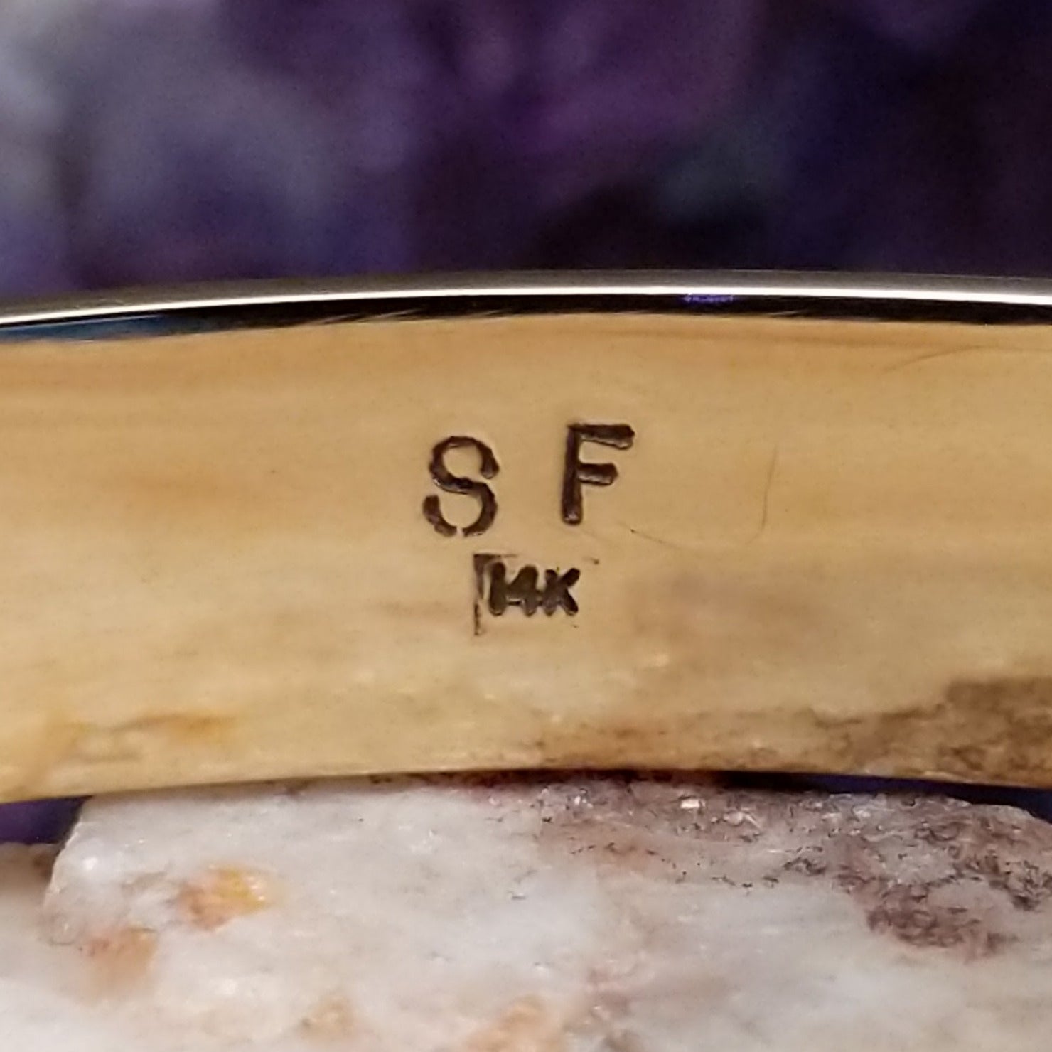 Close up of artist's stamped signature and stamped 14K, indicating 14 karat gold construction.