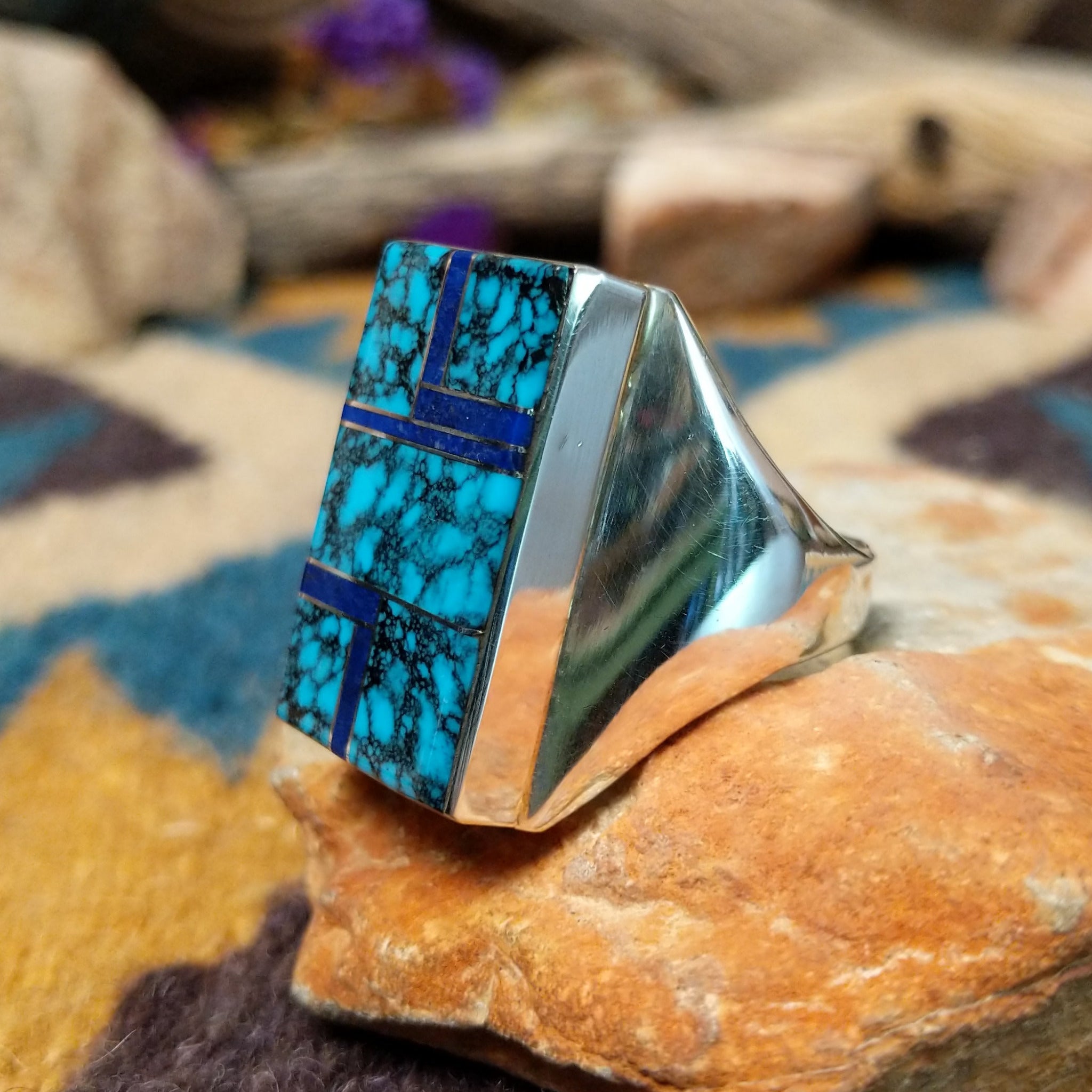 Sterling silver Navajo rectangle ring by Wilbert Grey featuring natural turquoise with black matrix and lapis lazuli geometric inlay in a polished signet-style setting; side view.