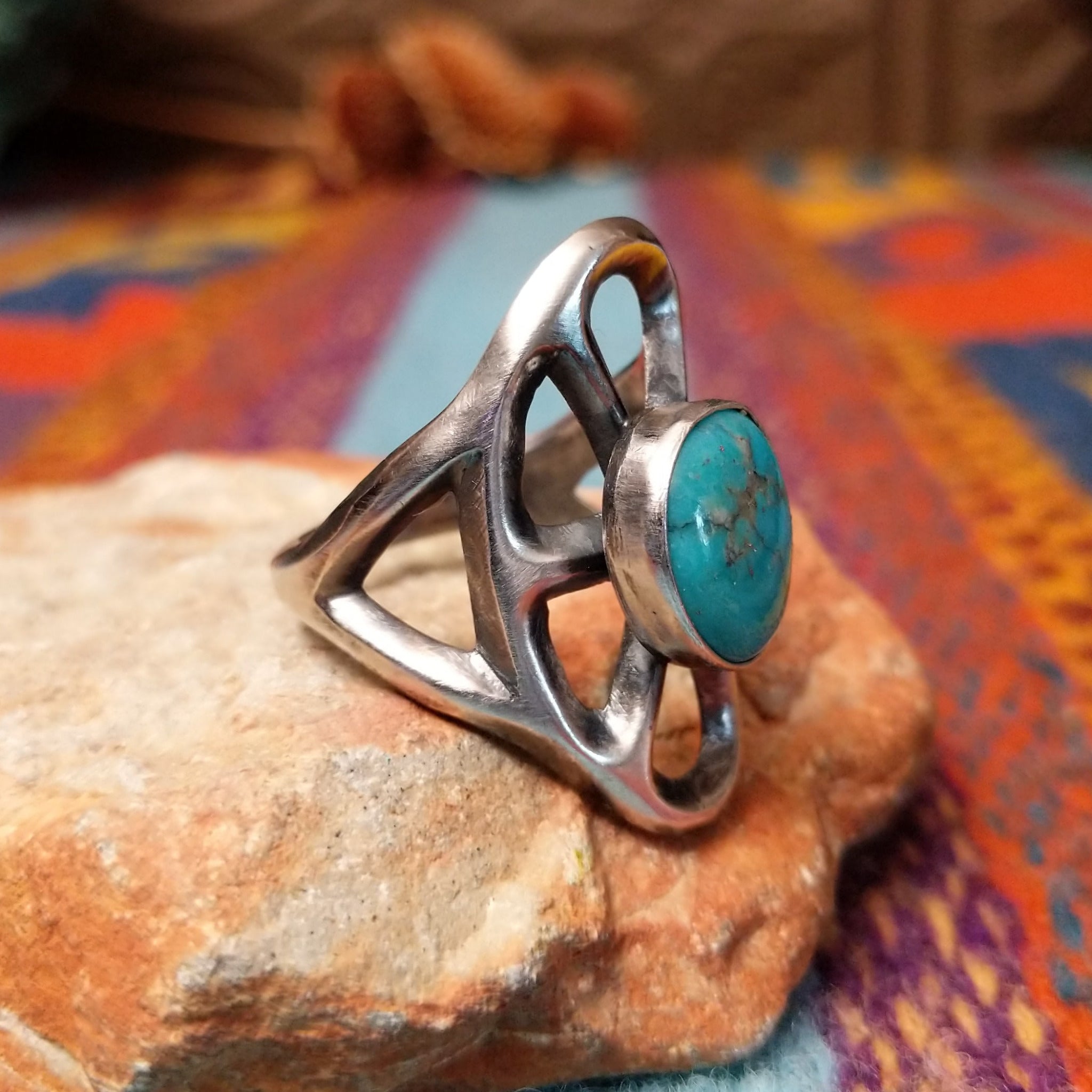 Turquoise Lattice Ring by Harry Morgan featuring an oval turquoise stone with natural matrix set in Sterling Silver, surrounded by bold sculpted lattice-style openwork; side view.