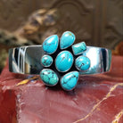 Sterling silver cuff bracelet with a cluster of turquoise set in various bezels.