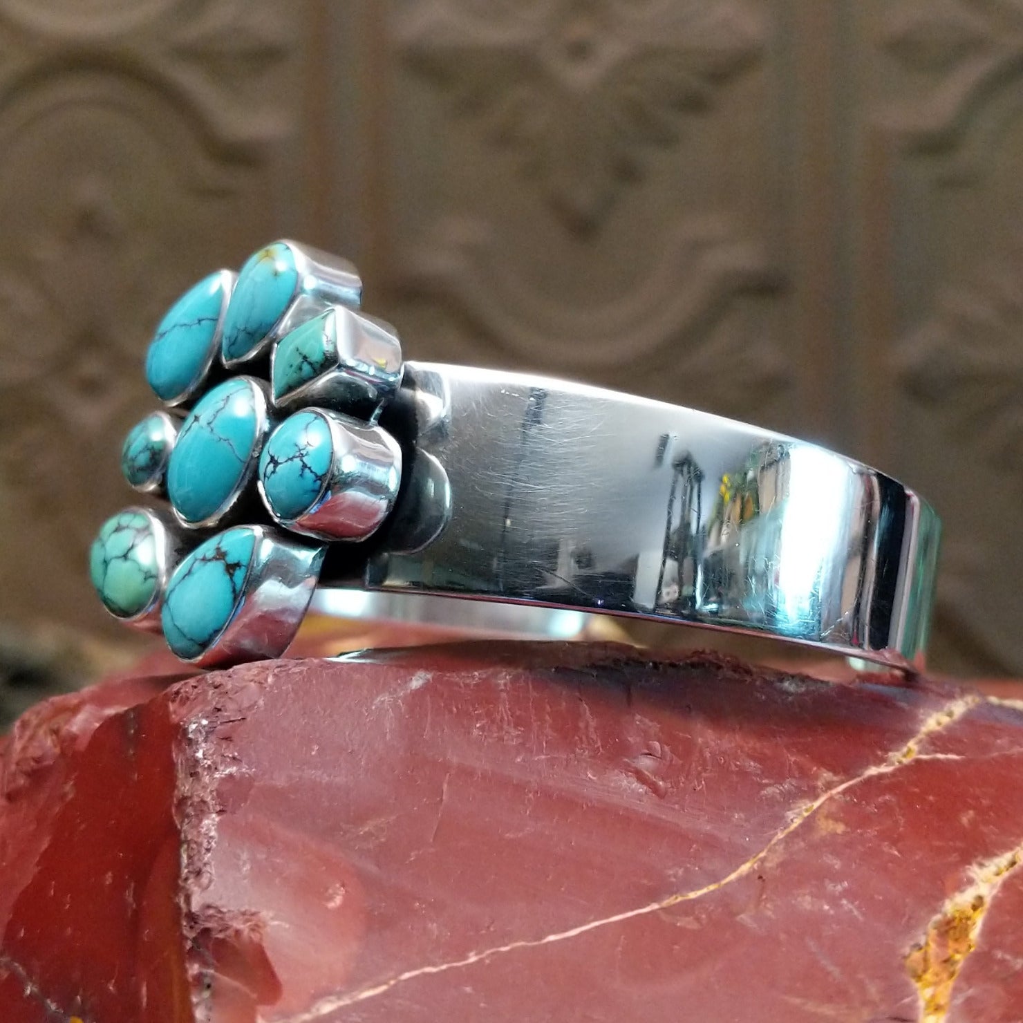 Sterling silver cuff bracelet with a cluster of turquoise set in various bezels.