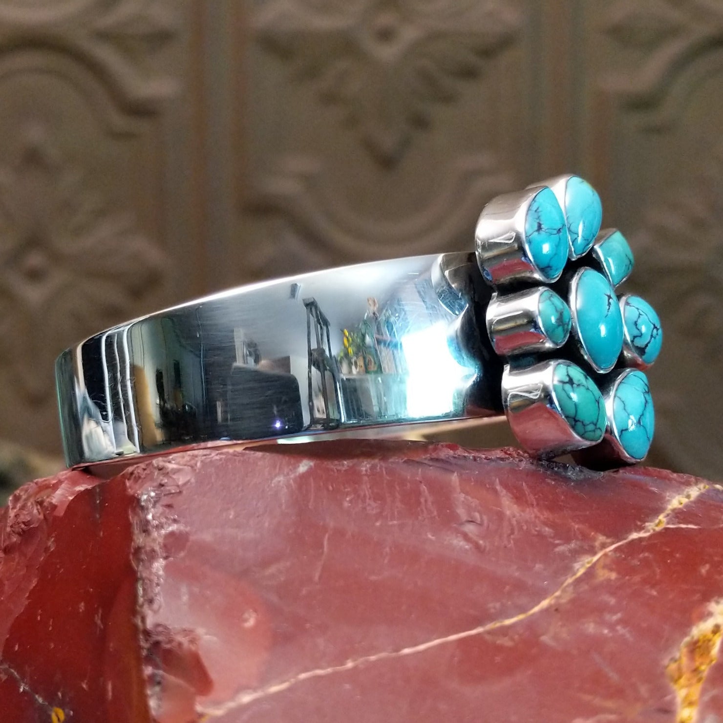 Sterling silver cuff bracelet with a cluster of turquoise set in various bezels.