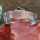 Sterling silver cuff bracelet with a cluster of turquoise set in various bezels.