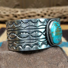 Turquoise Mountain turquoise cuff by E. Piaso, featuring a blue turquoise stone with a natural brown matrix set in a handcrafted wide sterling silver cuff; side view.