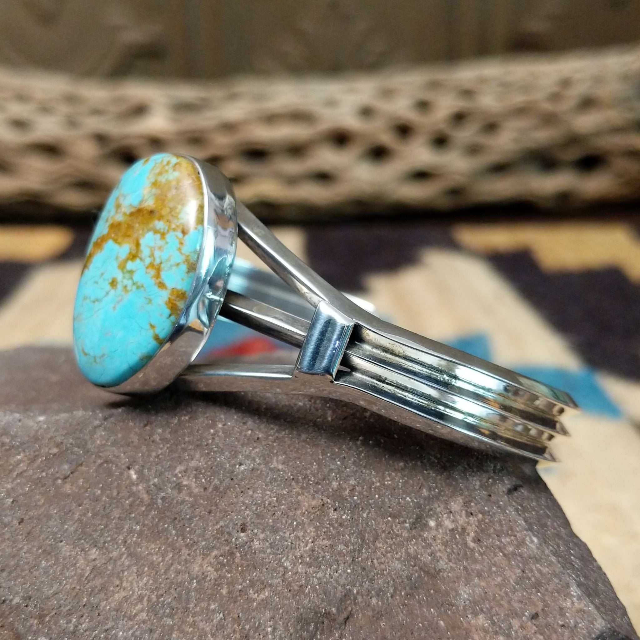 Turquoise Mountain turquoise cuff by Lucy Jake, featuring a blue turquoise stone with a natural brown matrix set in a handcrafted sterling silver cuff; side view.