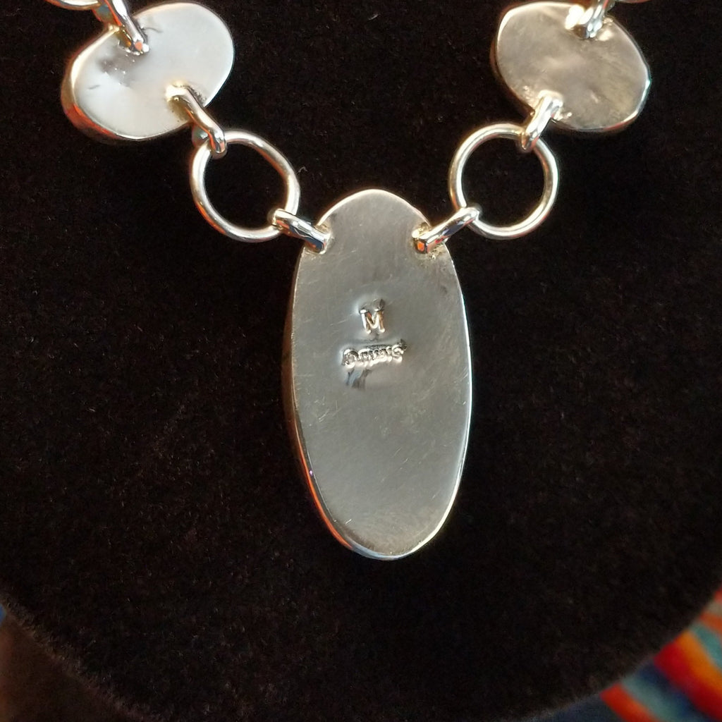 The artisan's initial is found on the back of the largest oval bezel.