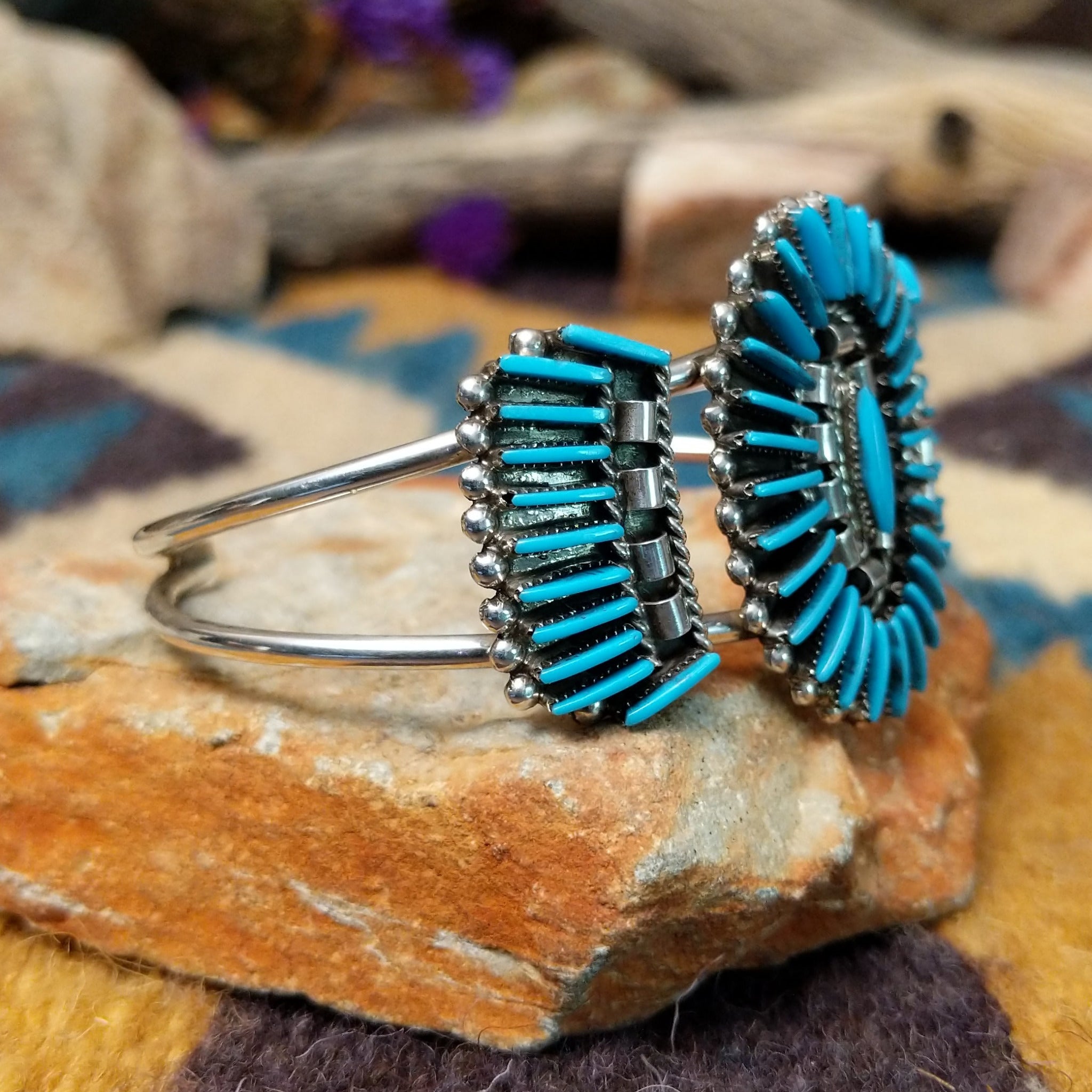 Handcrafted sterling silver cuff by Barton Cooeyate featuring a turquoise needlepoint concho centerpiece with matching side conchos, twisted rope detailing, silver bead accents, and a triple-shank cuff; side view.
