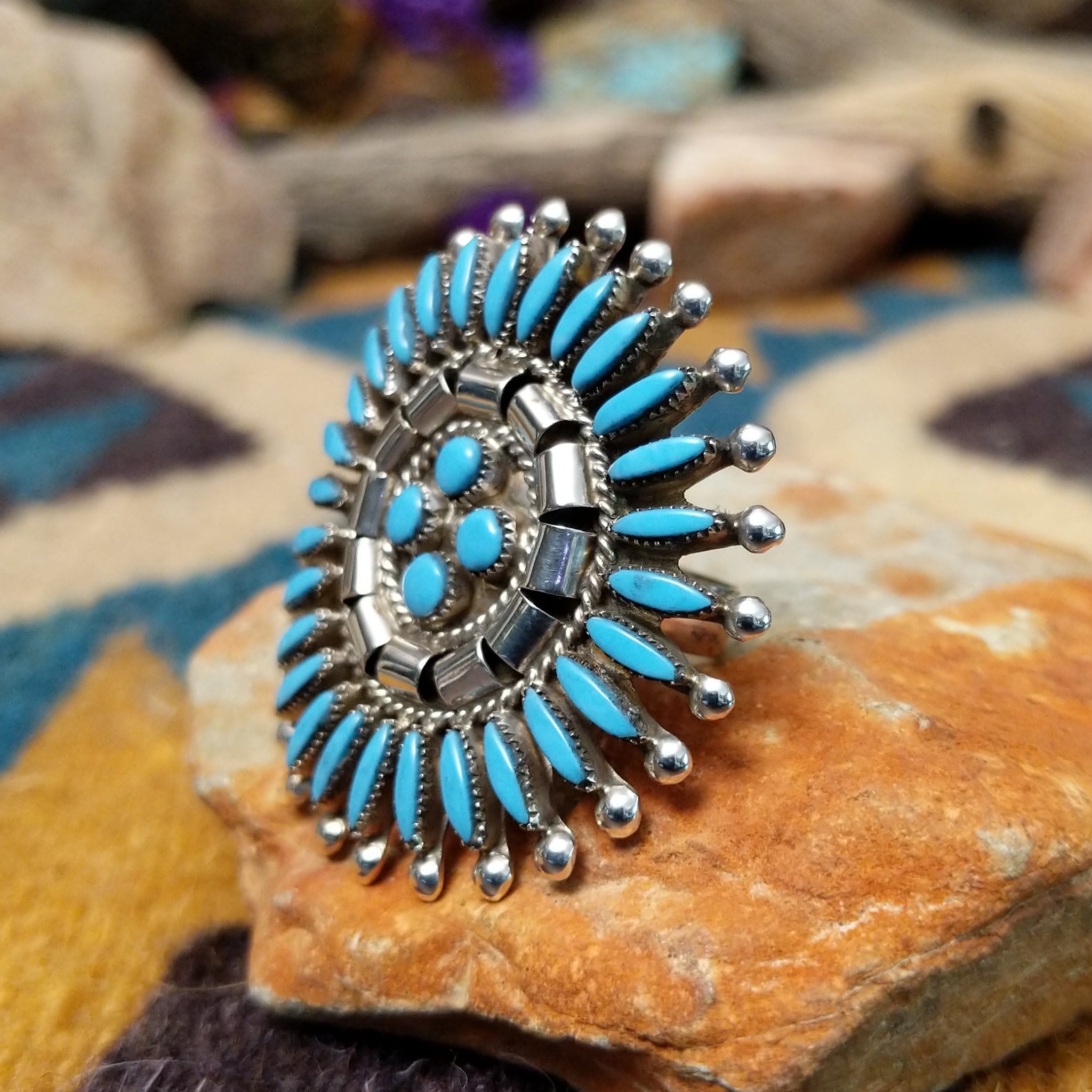 Handcrafted sterling silver Zuni concho ring featuring a turquoise needlepoint sunburst design with marquise-cut turquoise stones surrounding a central cluster of round turquoise cabochons, accented by polished silver details and twisted rope borders; side view.