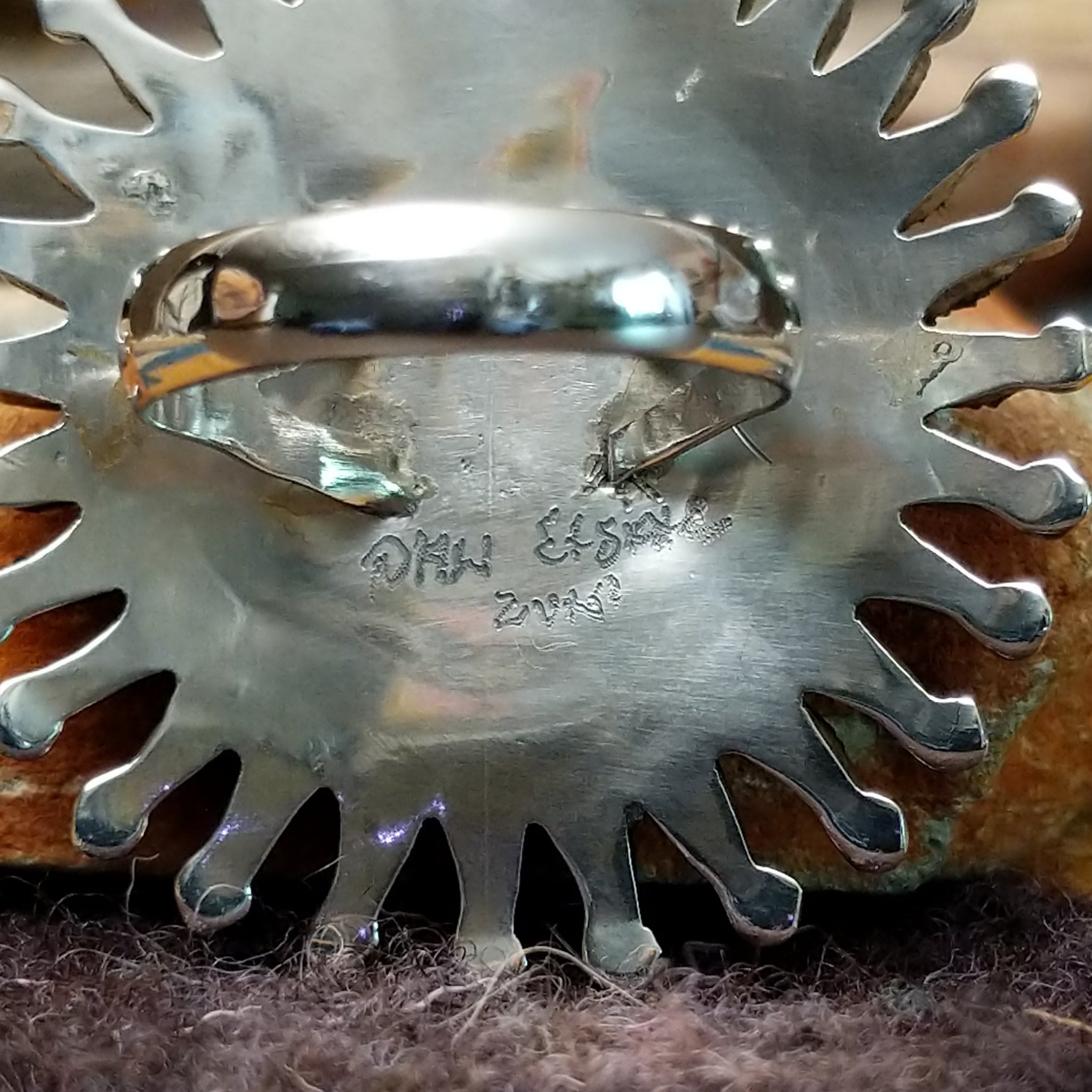 Handcrafted sterling silver Zuni concho ring featuring a turquoise needlepoint sunburst design with marquise-cut turquoise stones surrounding a central cluster of round turquoise cabochons, accented by polished silver details and twisted rope borders; artisan and tribe signature.