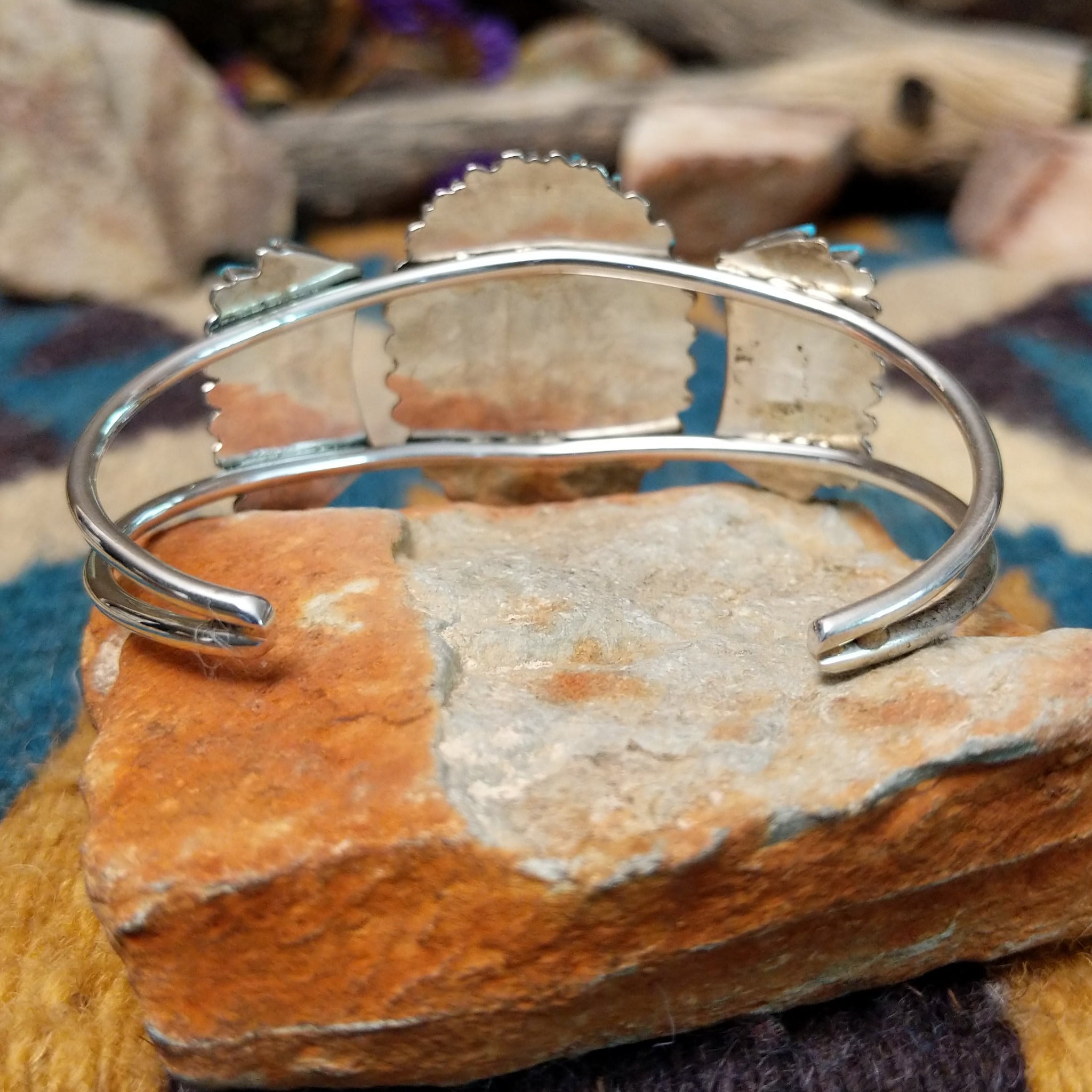 Handcrafted sterling silver cuff by Barton Cooeyate featuring a turquoise needlepoint concho centerpiece with matching side conchos, twisted rope detailing, silver bead accents, and a triple-shank cuff; underside view.