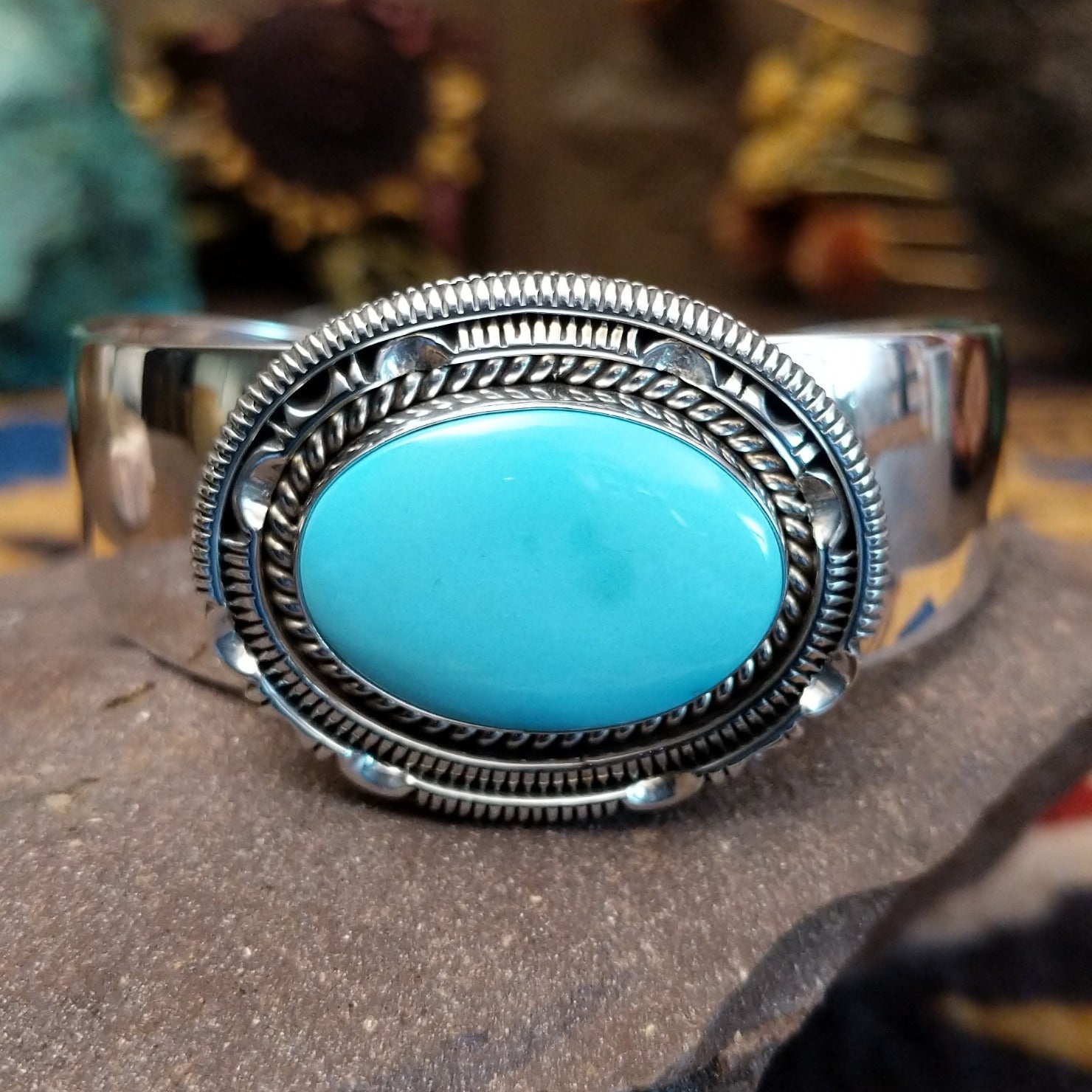 Silver cuff featuring an oval turquoise stone set in an intricate layered silver setting.