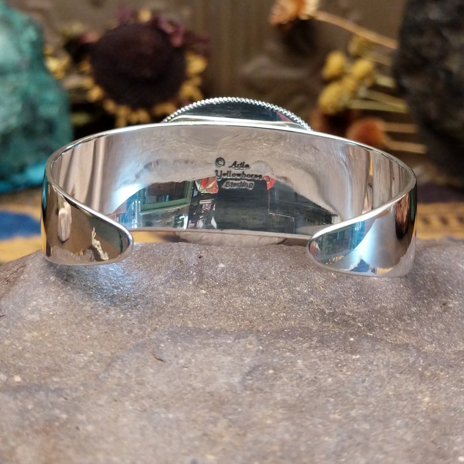 Silver cuff featuring an oval turquoise stone set in an intricate layered silver setting.