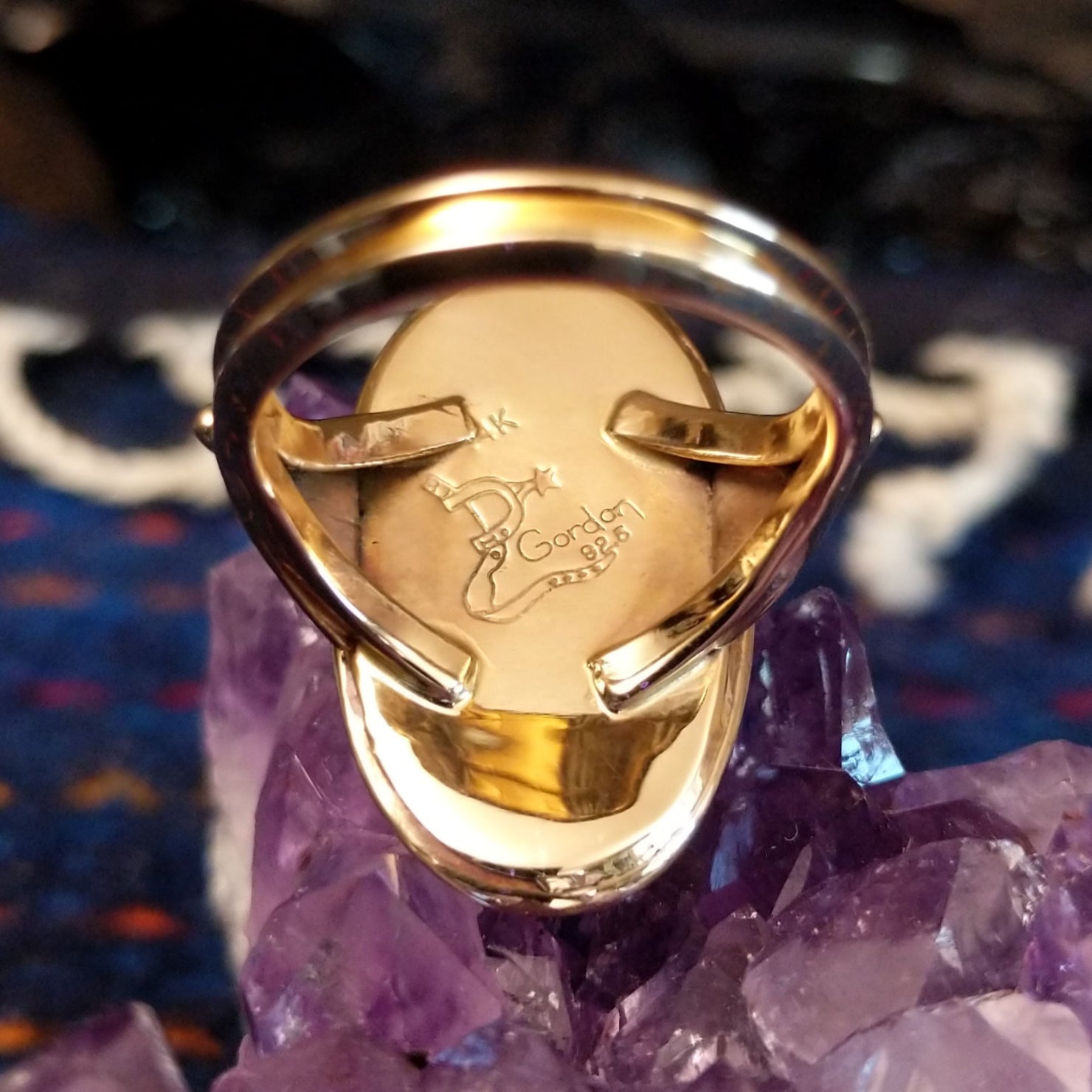 The artist's signature is etched into the inside of the ring.
