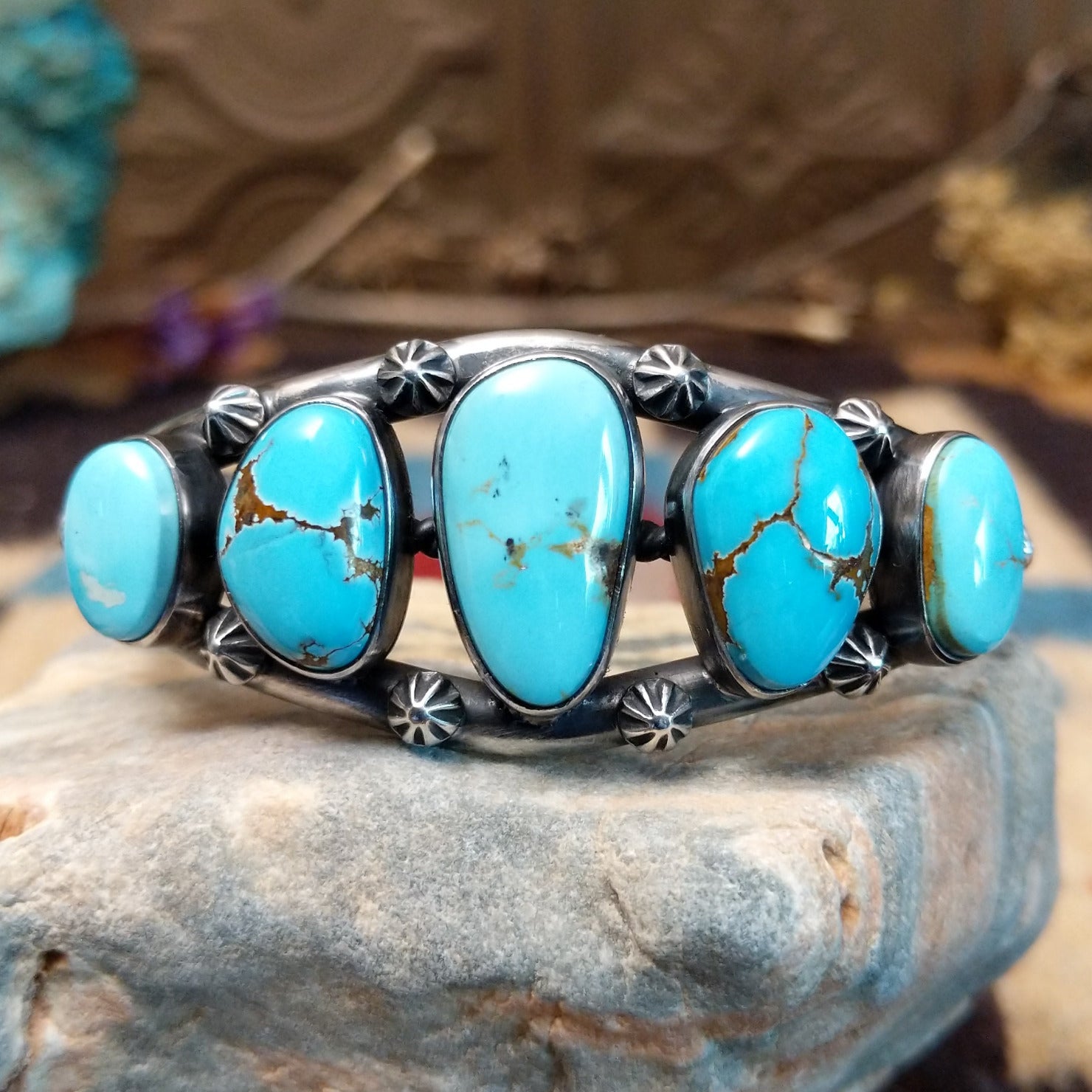 Sterling silver cuff bracelet with a quintet of turquoise set in bezels, framed by dotted and twisted rope accents.
