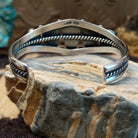 Sterling silver cuff bracelet with a quintet of turquoise set in bezels, framed by dotted and twisted rope accents.