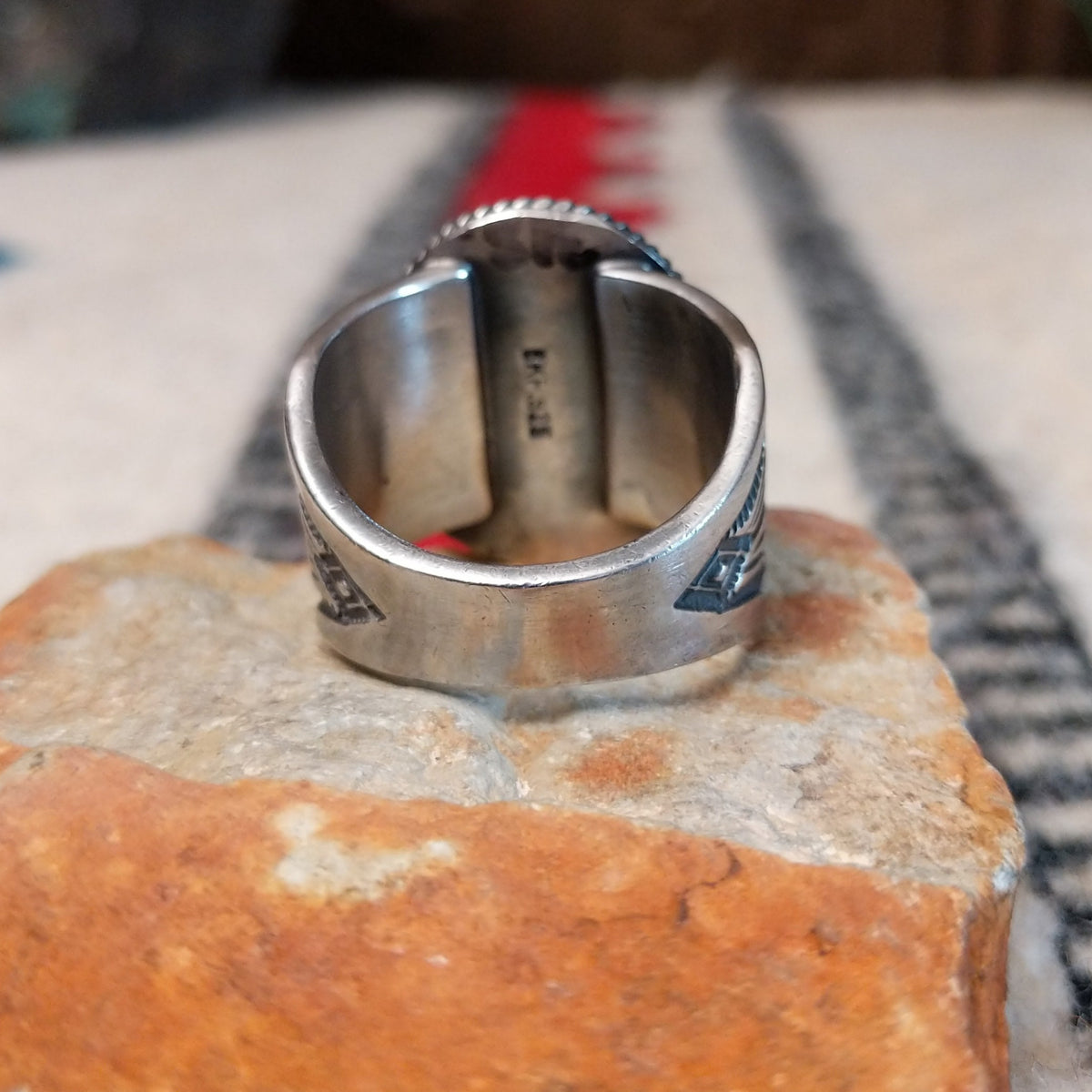 Turquoise ring by Burt Francisco featuring a large oval bright blue turquoise stone with subtle matrix, framed by twisted silver rope detailing on a wide silver band; underside view.