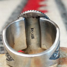 Turquoise ring by Burt Francisco featuring a large oval bright blue turquoise stone with subtle matrix, framed by twisted silver rope detailing on a wide silver band; artisan and .925 (Sterling Silver) stamp.
