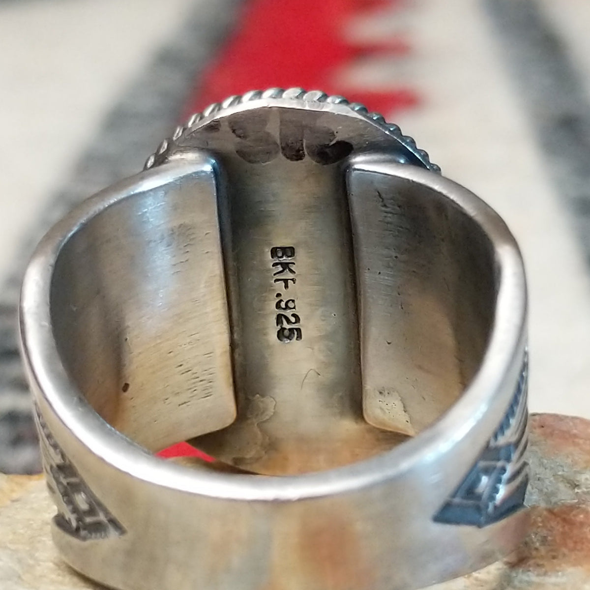 Turquoise ring by Burt Francisco featuring a large oval bright blue turquoise stone with subtle matrix, framed by twisted silver rope detailing on a wide silver band; artisan and .925 (Sterling Silver) stamp.
