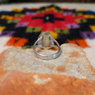 This Turquoise Ring by Byron Begay features a bright blue oval turquoise stone set in sterling silver with a twisted rope border and split-shank band; underside view.