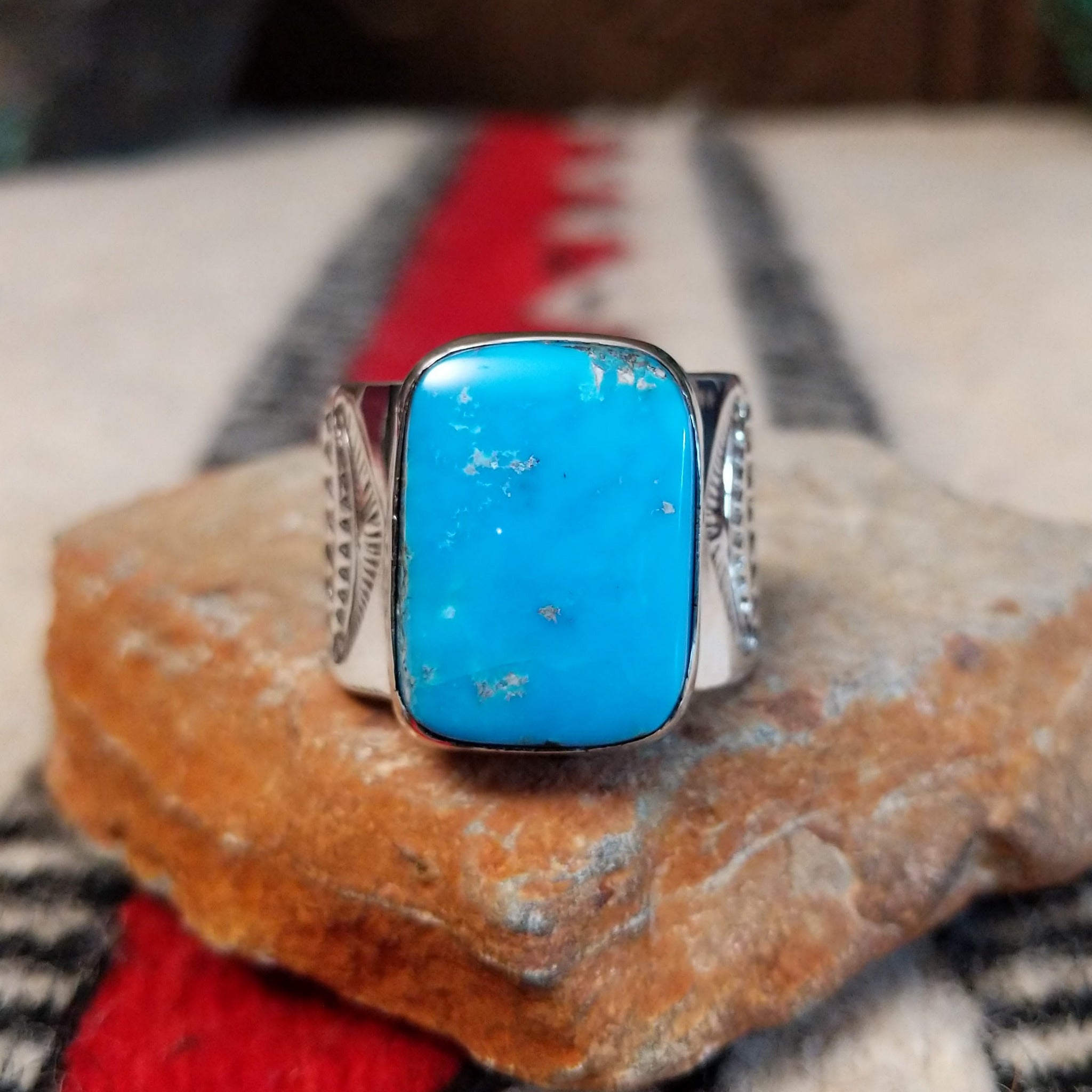 Turquoise ring by Lucy Jake featuring a large rectangular bright blue turquoise stone with subtle natural matrix, set in a wide silver band with stamped detailing.