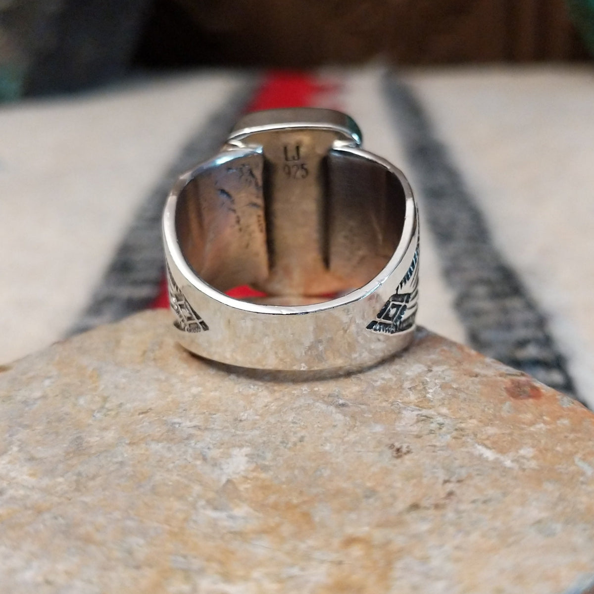 Turquoise ring by Lucy Jake featuring a large rectangular bright blue turquoise stone with subtle natural matrix, set in a wide silver band with stamped detailing; underside view.