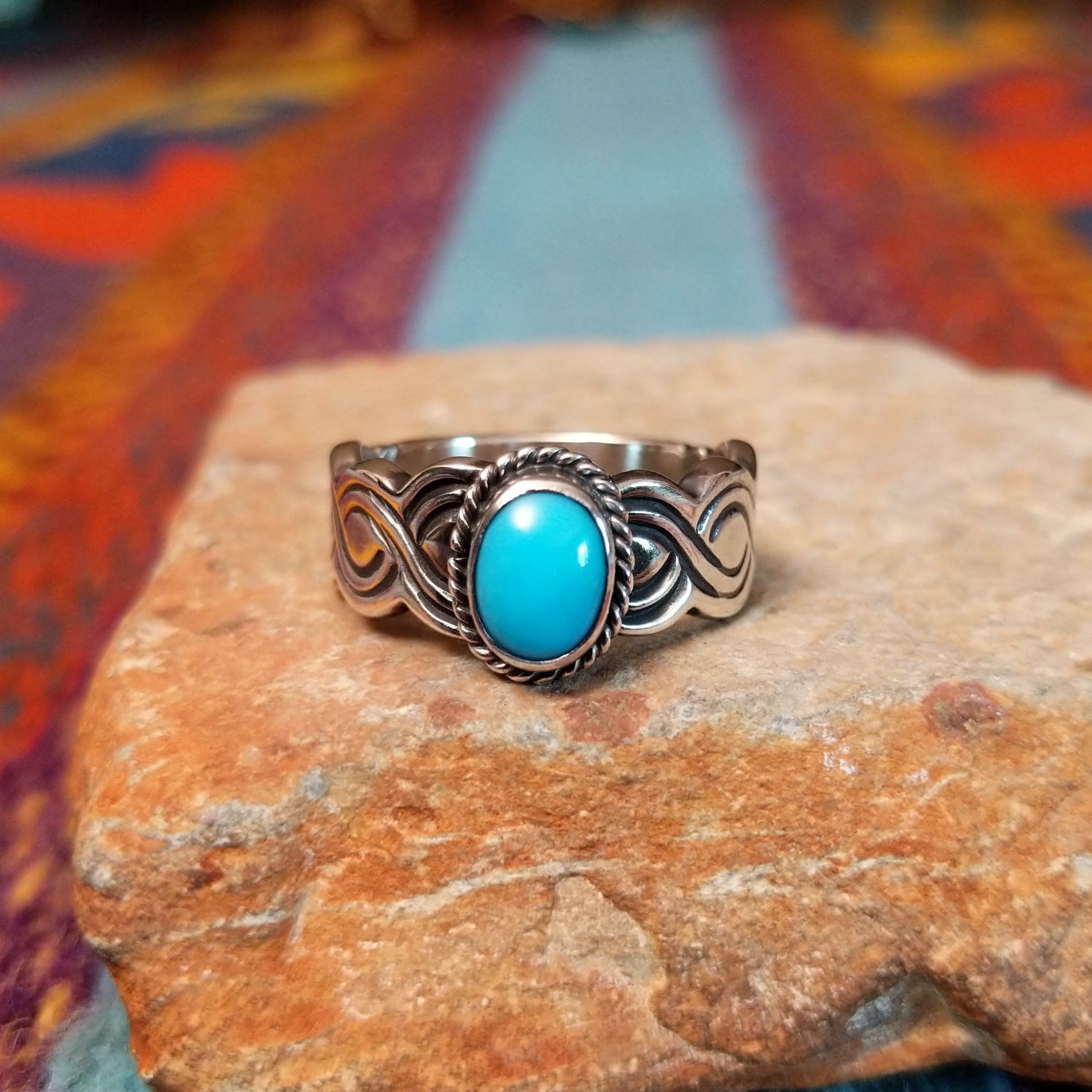 Turquoise ring by Raymond Coriz with oval stone, twisted border, and curved silverwork.