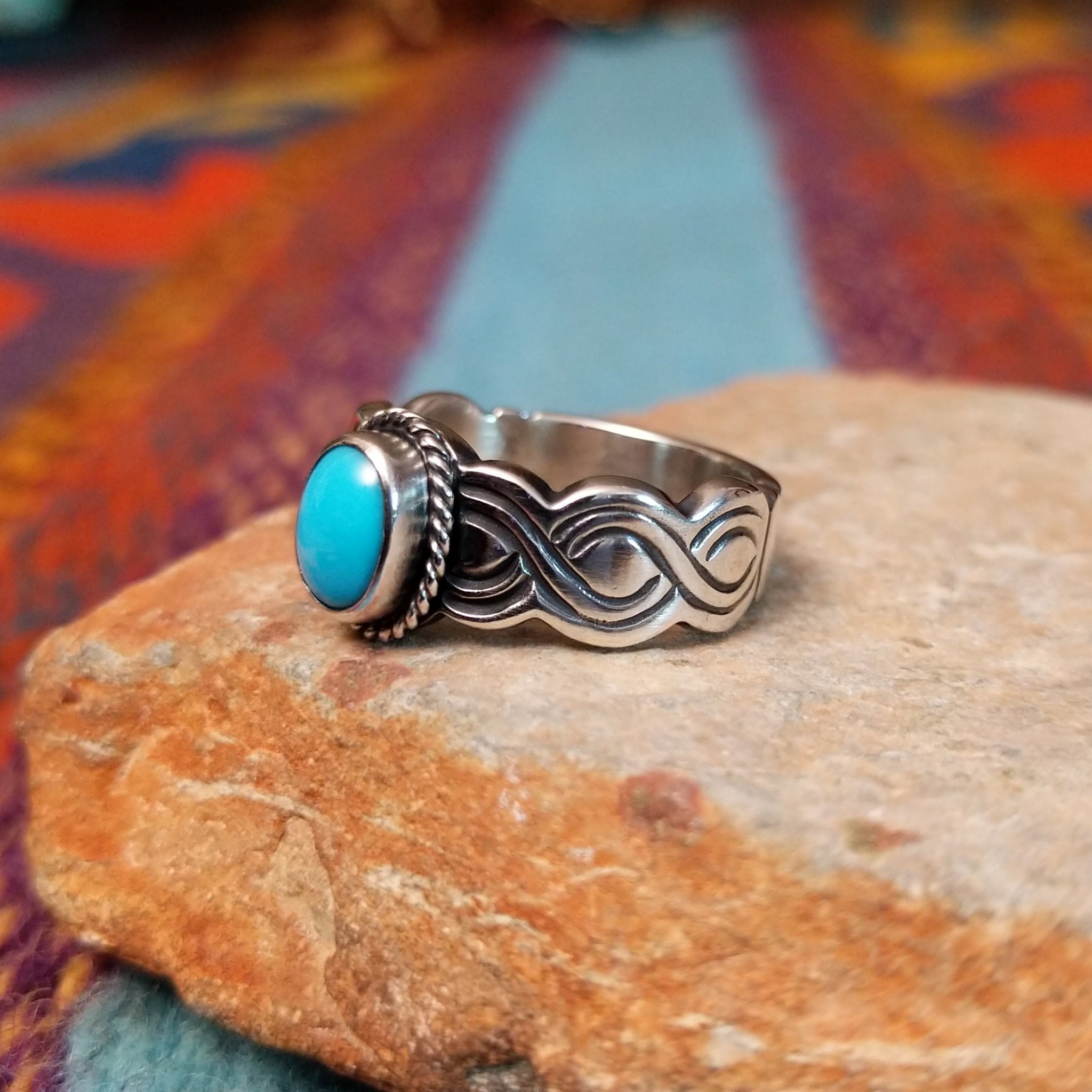 Turquoise ring by Raymond Coriz with oval stone, twisted border, and curved silverwork.