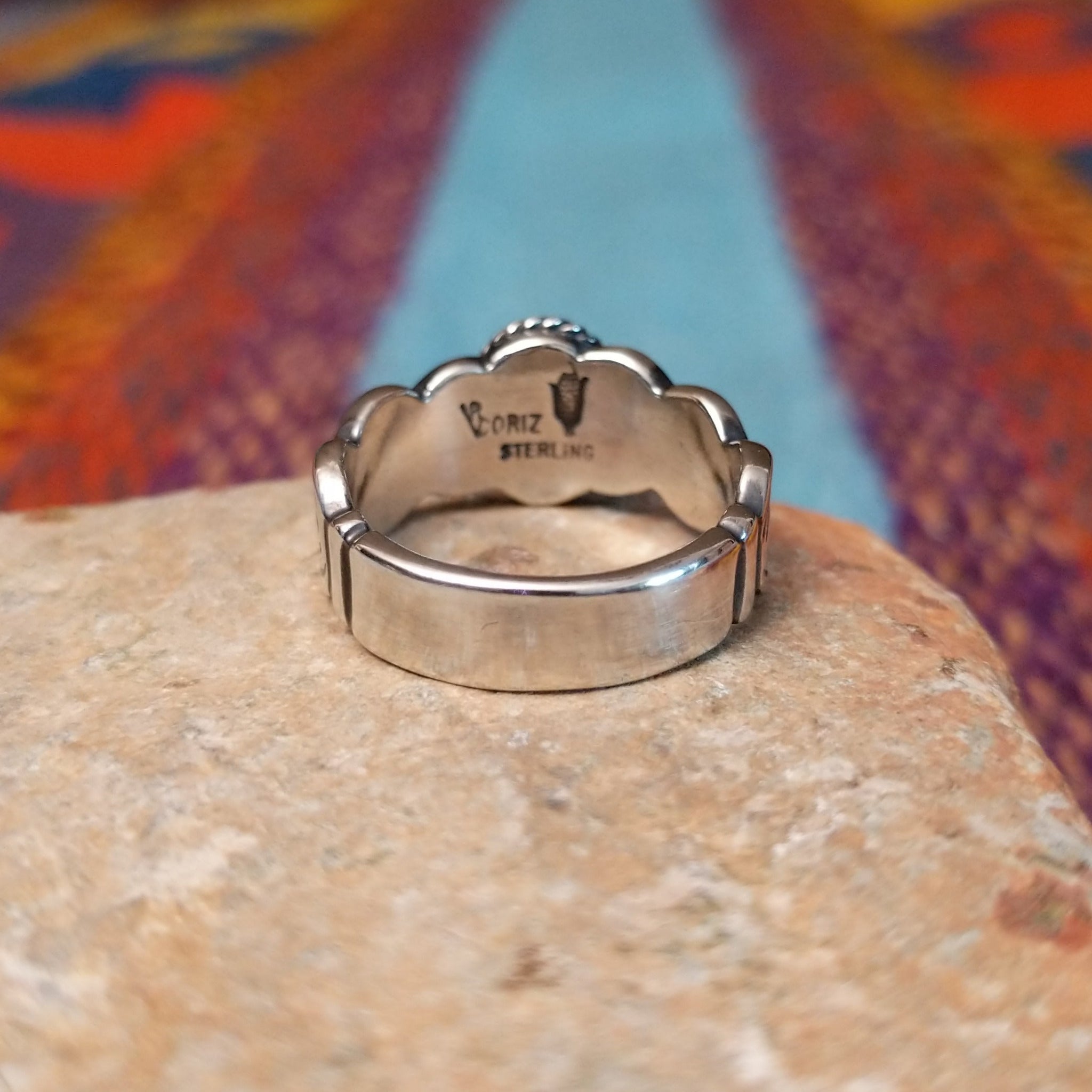 Turquoise ring by Raymond Coriz with oval stone, twisted border, and curved silverwork.
