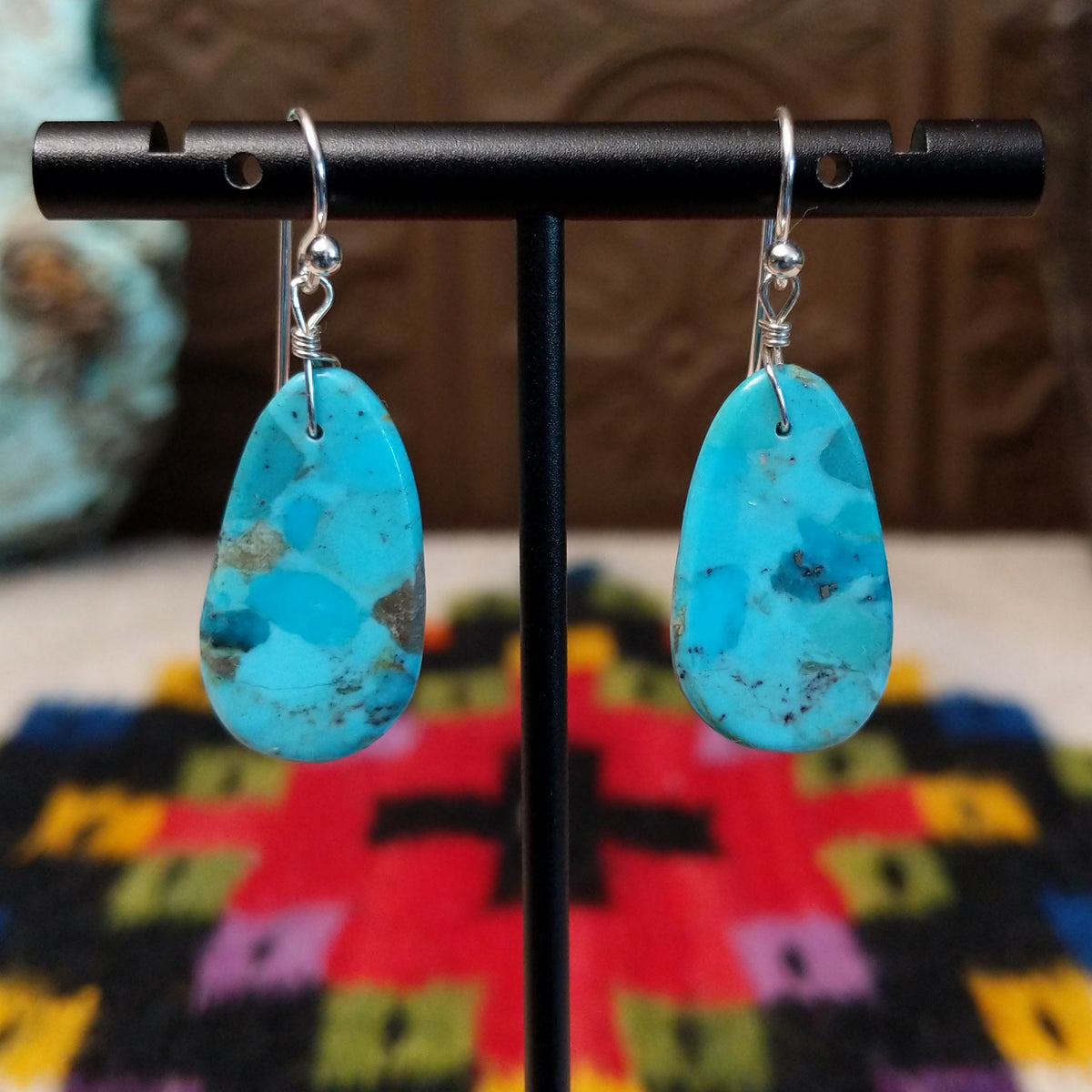 Turquoise Slab Earrings by Ronald Chavez featuring elongated freeform blue turquoise stones with natural tan, brown, and dark matrix, suspended from silver-tone hooks.