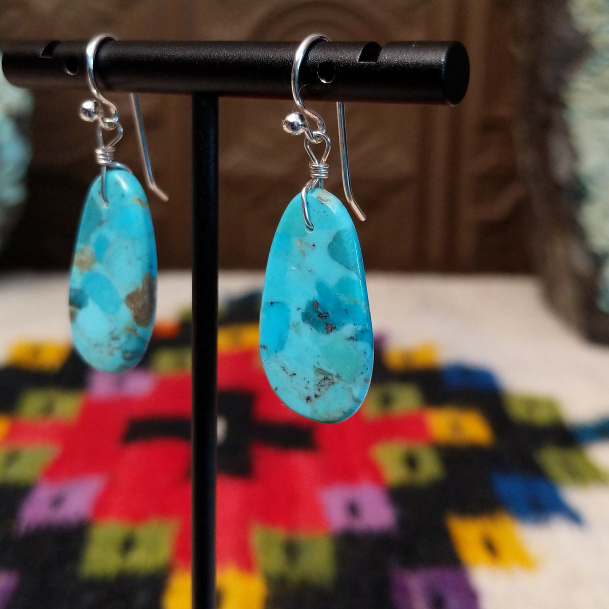 Turquoise Slab Earrings by Ronald Chavez featuring elongated freeform blue turquoise stones with natural tan, brown, and dark matrix, suspended from silver-tone hooks; side view.
