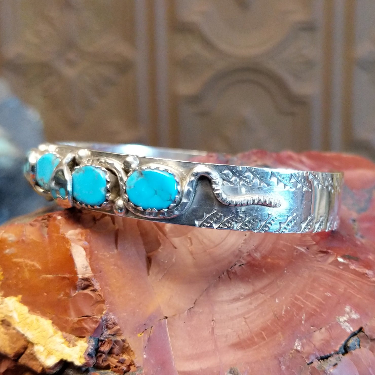 Sterling silver cuff bracelet with turquoise set in notched bezels and silverwork formed as a snake along the surface.