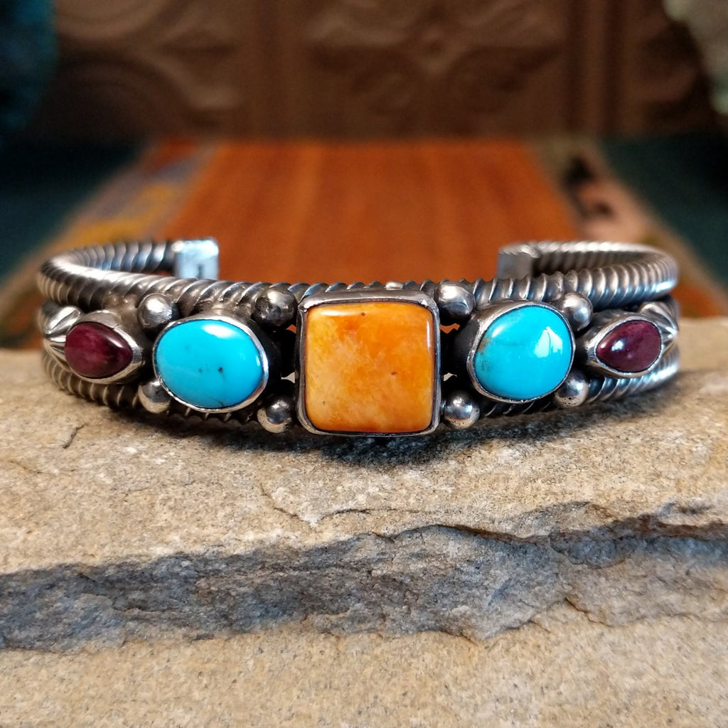 Patterned turquoise and spiny oyster shells set in sterling silver with dotted accents and layered coil cuff design.