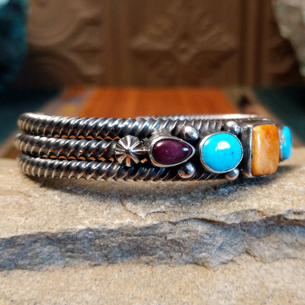 Patterned turquoise and spiny oyster shells set in sterling silver with dotted accents and layered coil cuff design.