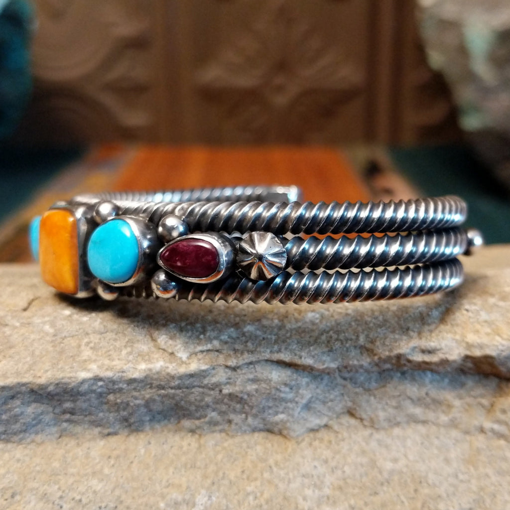 Patterned turquoise and spiny oyster shells set in sterling silver with dotted accents and layered coil cuff design.