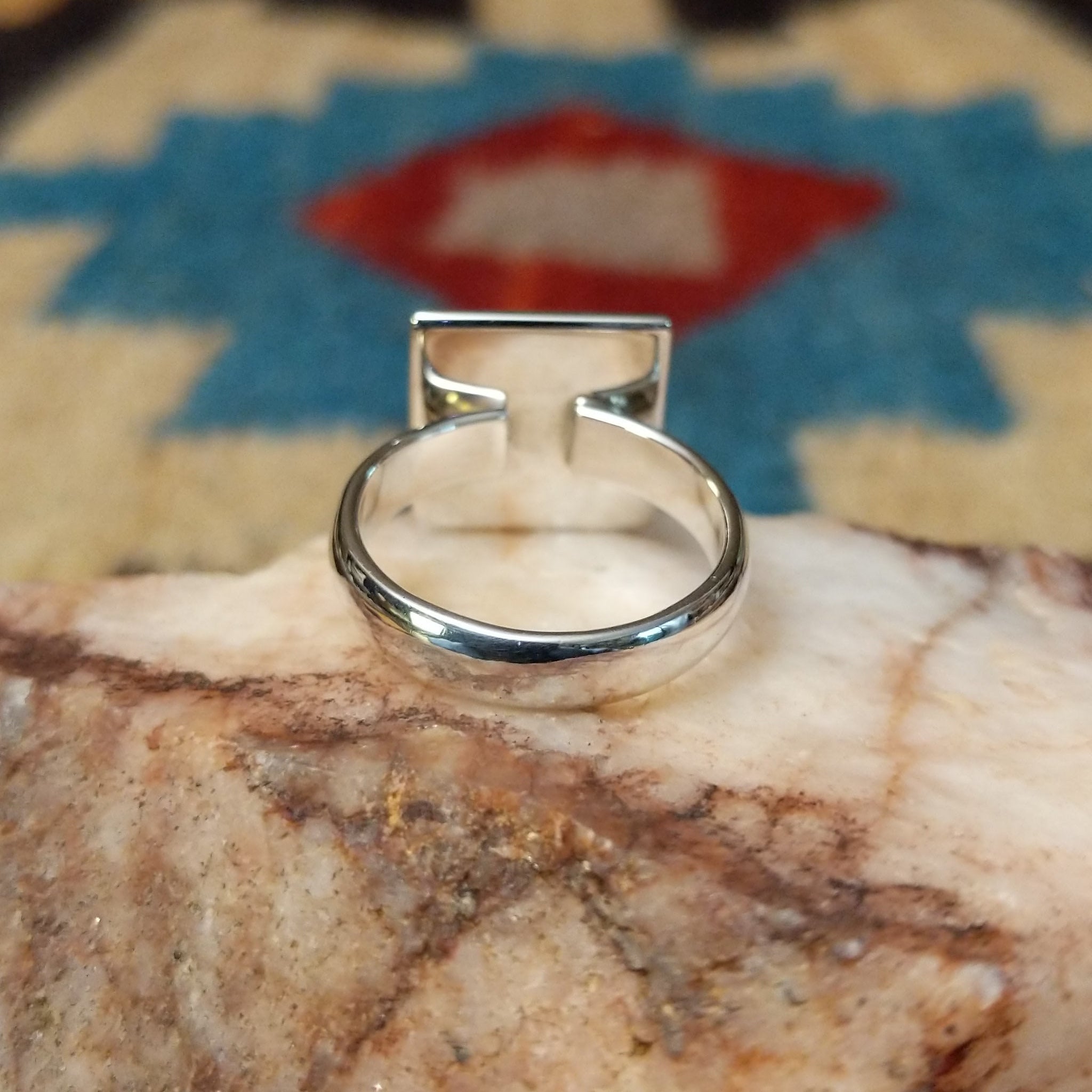 Turquoise square ring by Ann Curley, featuring a vibrant square turquoise stone with natural blue tones and matrix set in a handcrafted sterling silver band.  Underside view.