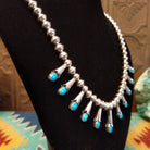 Beaded sterling silver necklace with multiple squash blossom pendants and turquoise set in notched bezels.