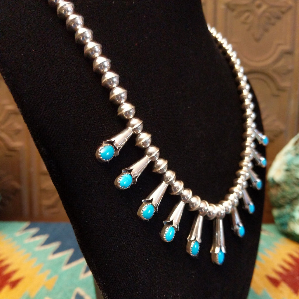 Beaded sterling silver necklace with multiple squash blossom pendants and turquoise set in notched bezels.