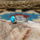 Turquoise strand ring by Angela Martin, featuring a round blue turquoise stone set in a handcrafted sterling silver multi-strand band with a polished finish.  Side view.
