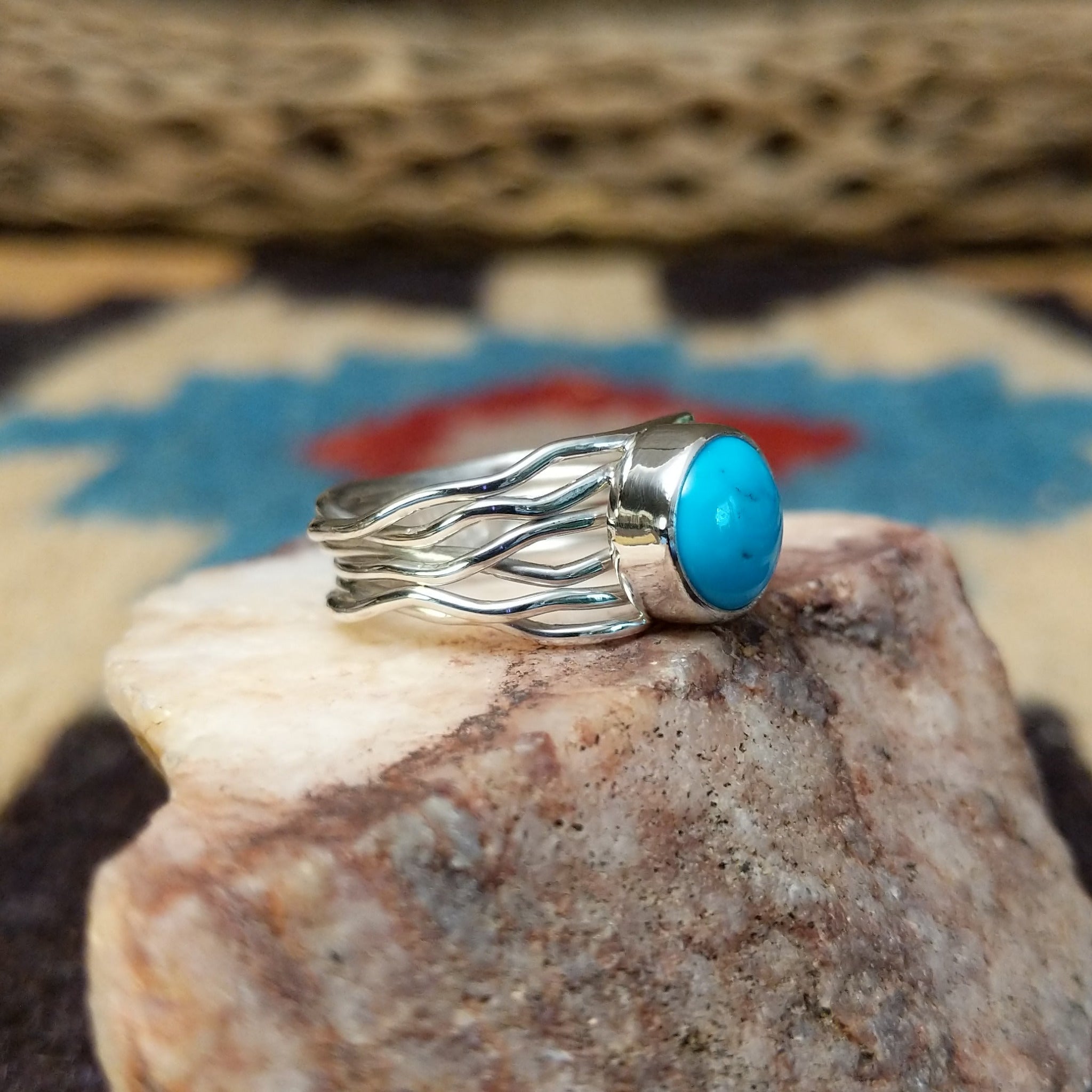 Turquoise strand ring by Angela Martin, featuring a round blue turquoise stone set in a handcrafted sterling silver multi-strand band with a polished finish.  Side view.