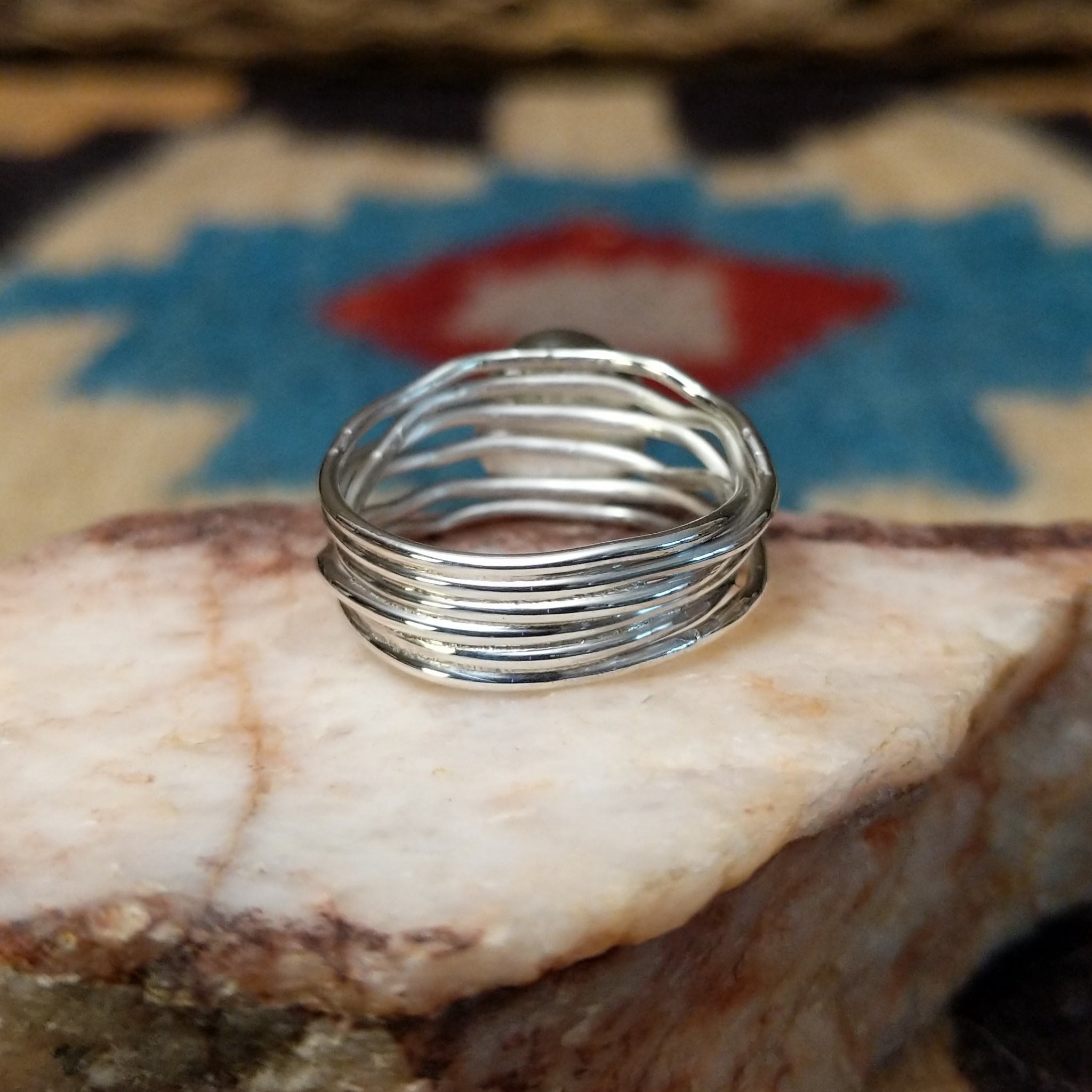Turquoise strand ring by Angela Martin, featuring a round blue turquoise stone set in a handcrafted sterling silver multi-strand band with a polished finish.  Underside view.