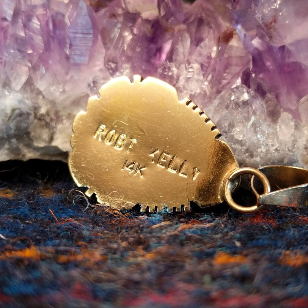 The back of the pendant features the artist's signature and gold stamp.