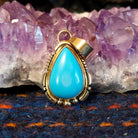 Turquoise teardrop pendant set in polished gold.