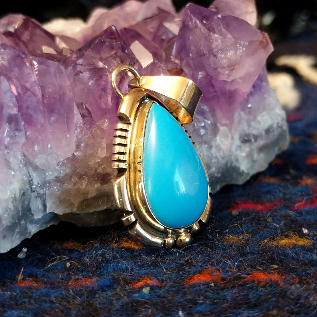 Turquoise teardrop pendant set in polished gold.