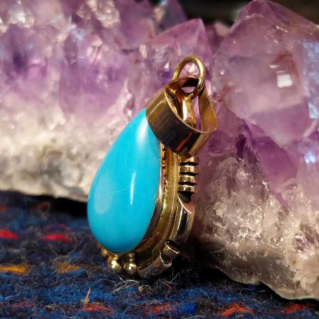 Turquoise teardrop pendant set in polished gold.