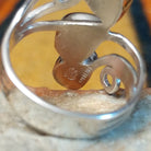 Close-up of the underside of a silver turquoise ring by Raymond Coriz showing the openwork band, curled silver accent, and stamped artist's signature alongside a sterling hallmark.