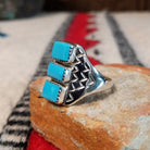 Three-stone turquoise silver ring by Pauline Nelson with stamped details.