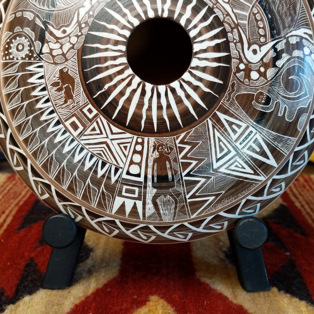 Decorative pottery with intricate white carvings on a patterned surface