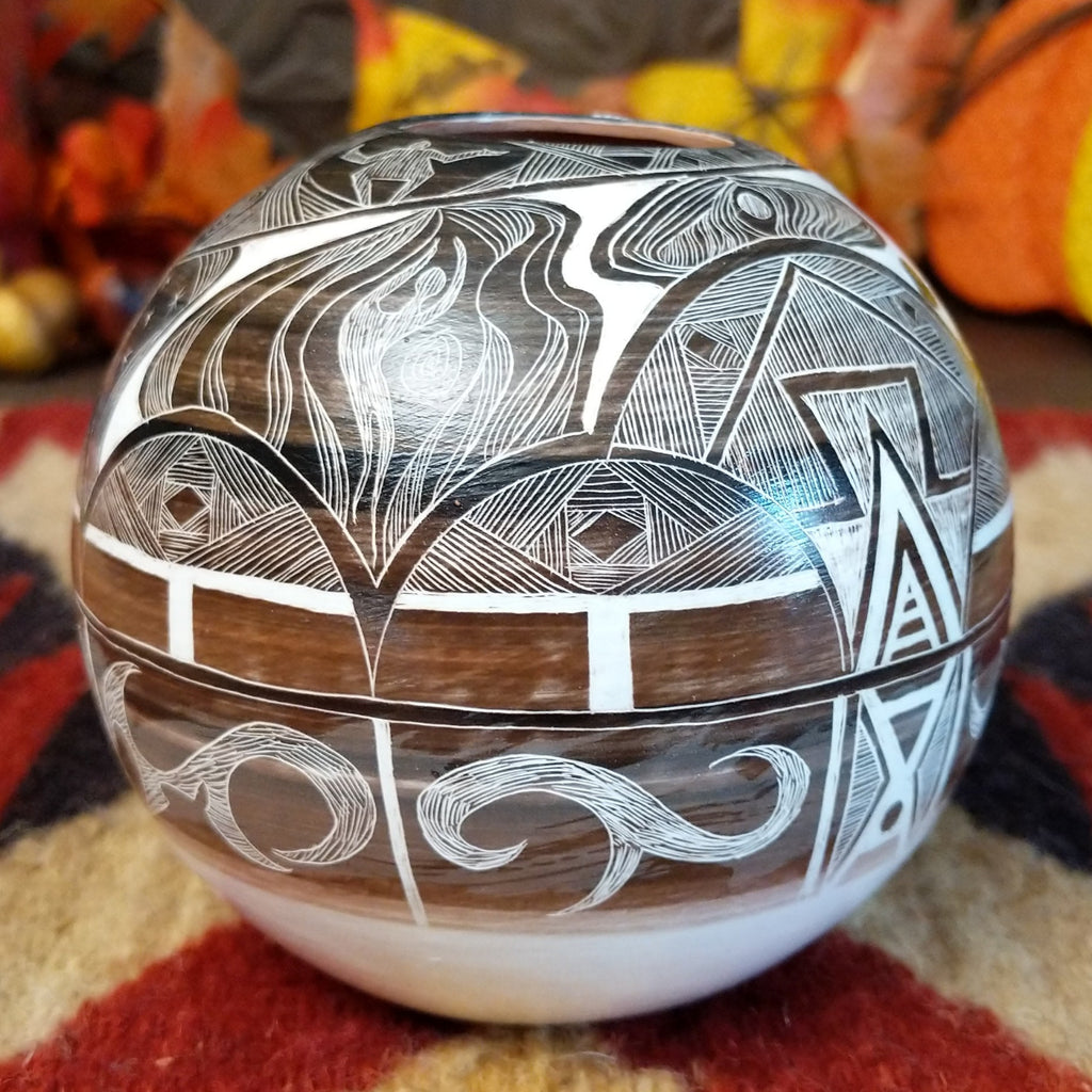 White clay with brown accents creating a pottery piece with intricately carved designs all along the surface.