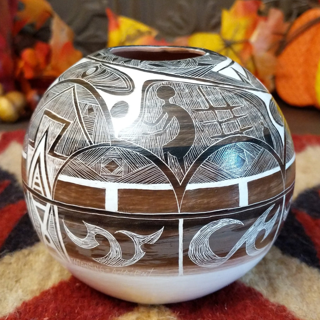 White clay with brown accents creating a pottery piece with intricately carved designs all along the surface.