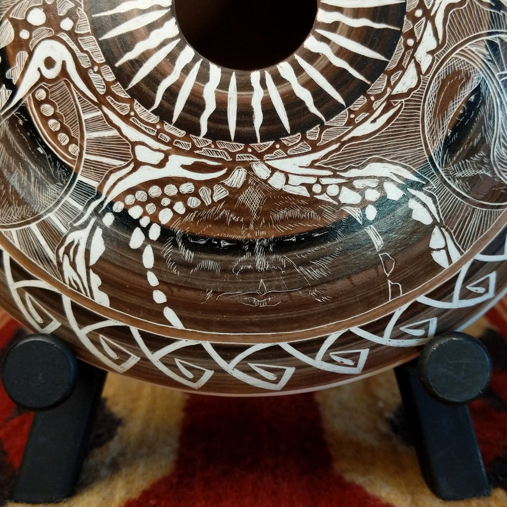 Close-up of an animal face design with intricate white carvings on pottery